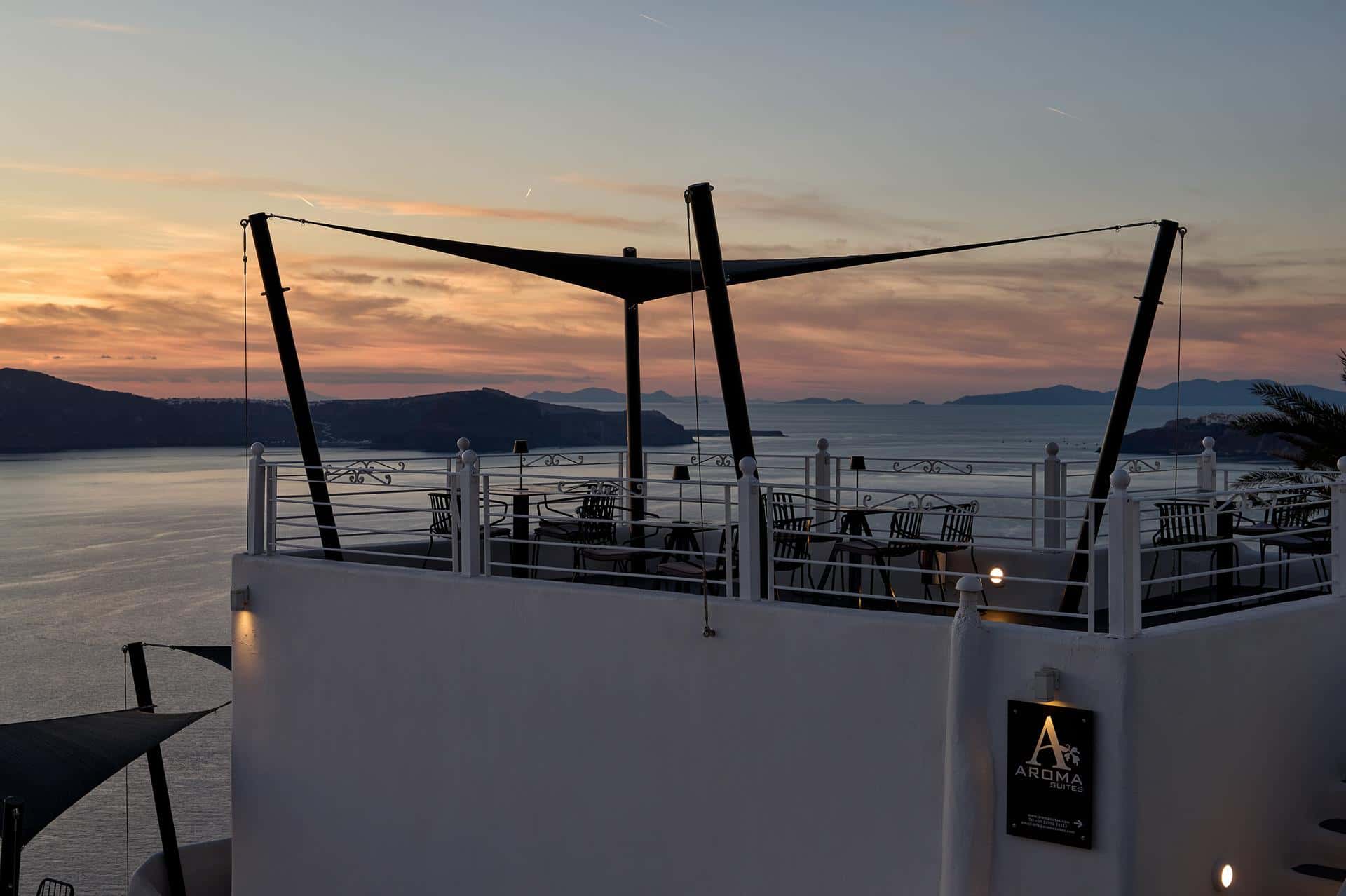 Rooftop terrace with sail shade at sunset with Aroma Suites sign visible