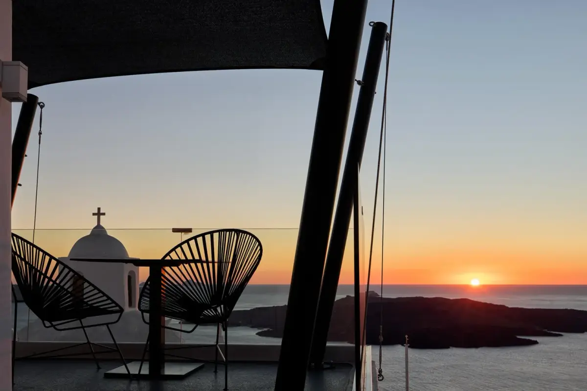 Two chairs on a terrace at Aroma Suites in Fira, facing the sunset over the caldera