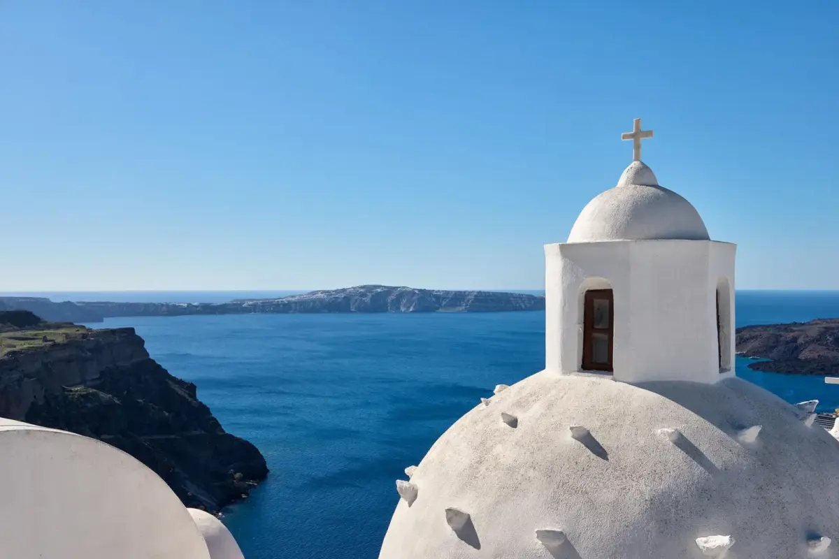 A white church dome and the blue caldera seen from a terrace at Aroma Suites in Fira