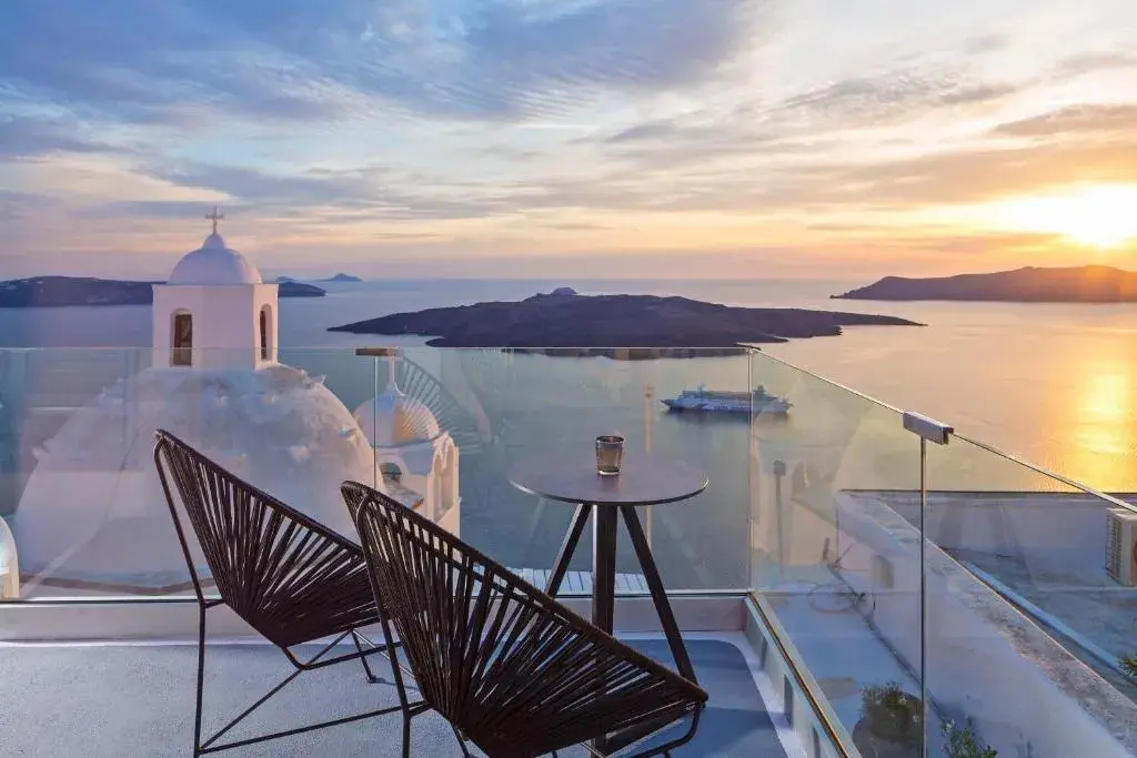 Two chairs on a terrace at Aroma Suites, with Nea Kameni and the evening sun over the caldera