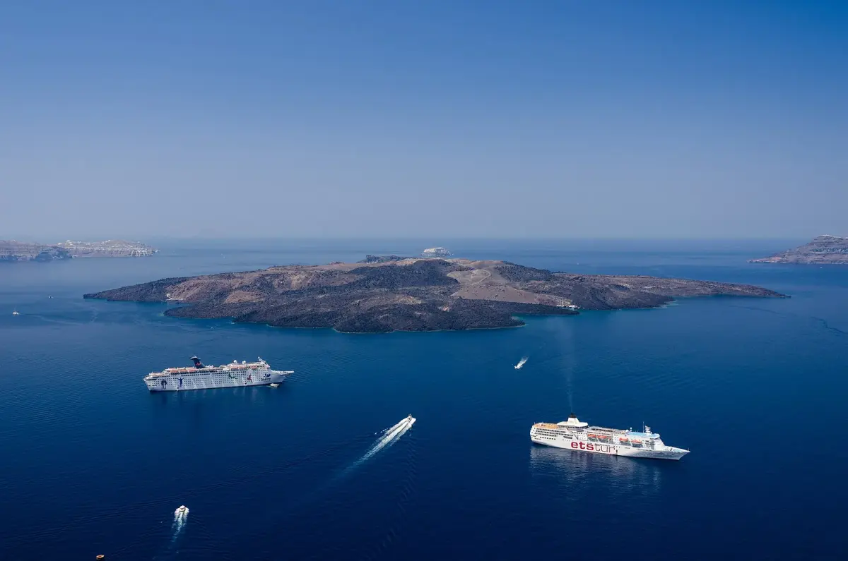 Deep blue caldera with Nea Kameni and two cruise ships, seen from high above Fira