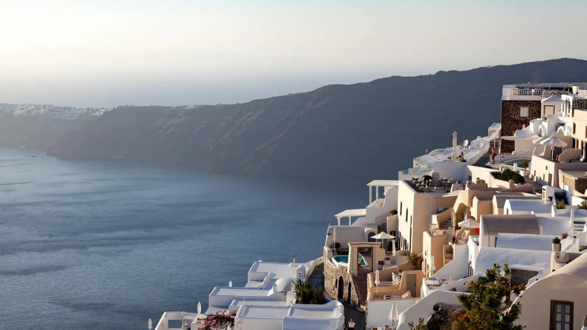 Whitewashed Santorini architecture with caldera sea views from a hotel terrace at sunset