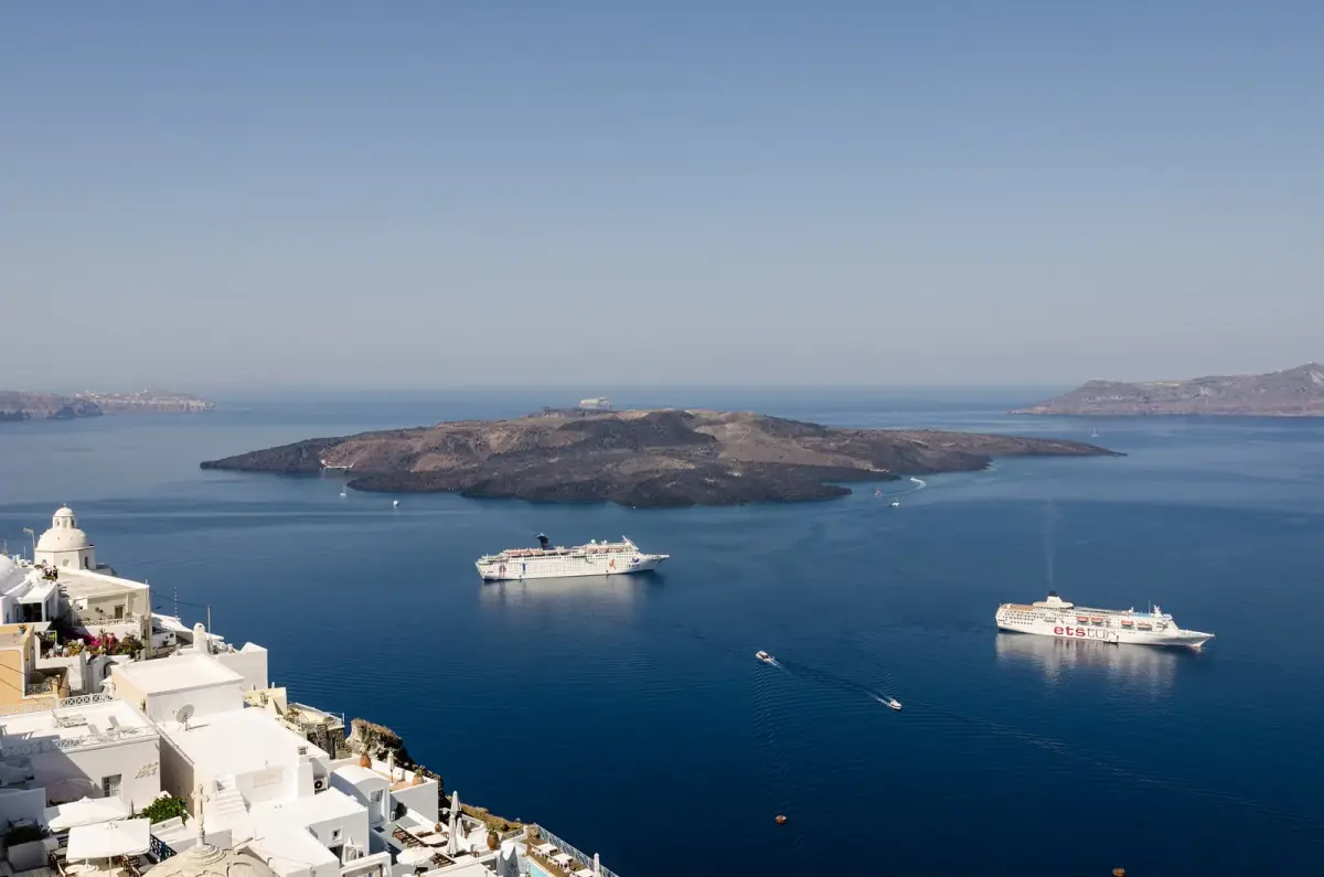 Fira's whitewashed houses on the caldera edge looking out over the volcanic island of Nea Kameni and two cruise ships