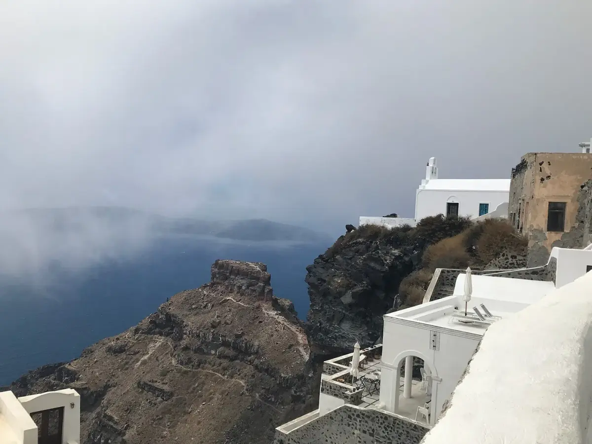 Skaros Rock below Imerovigli's white chapel and houses, low cloud over the caldera