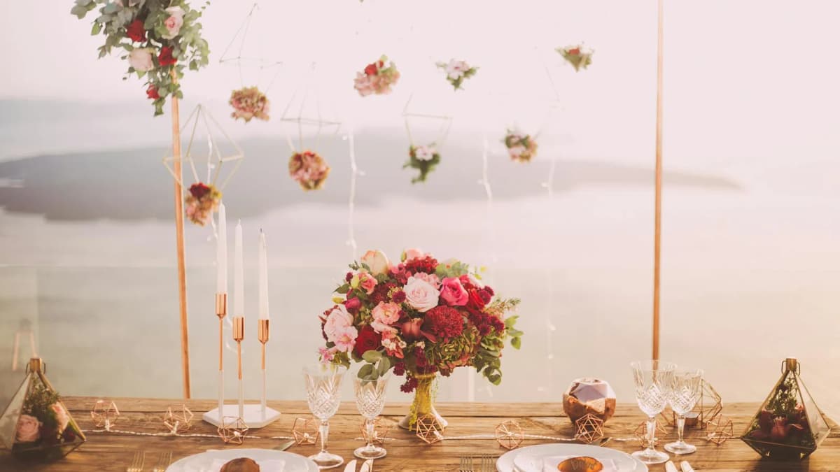 Romantic dinner setup with candles and flowers overlooking the Santorini caldera at sunset