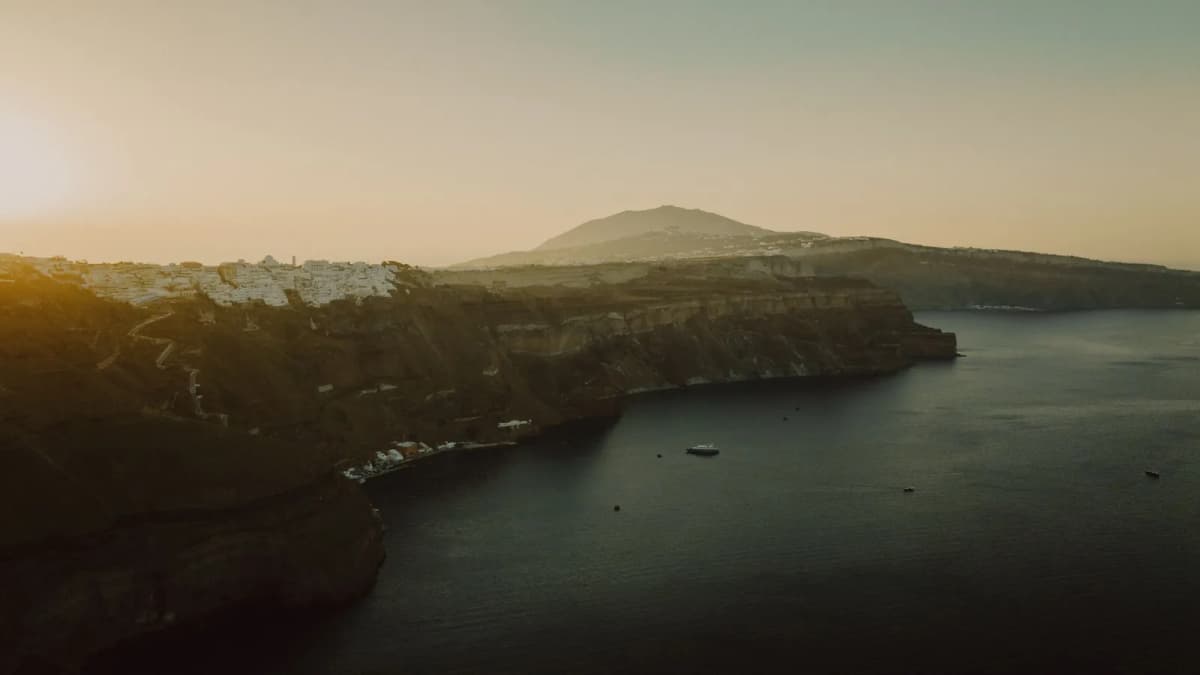Aerial view of the Santorini caldera cliffs rising from deep blue water with Fira village on the rim