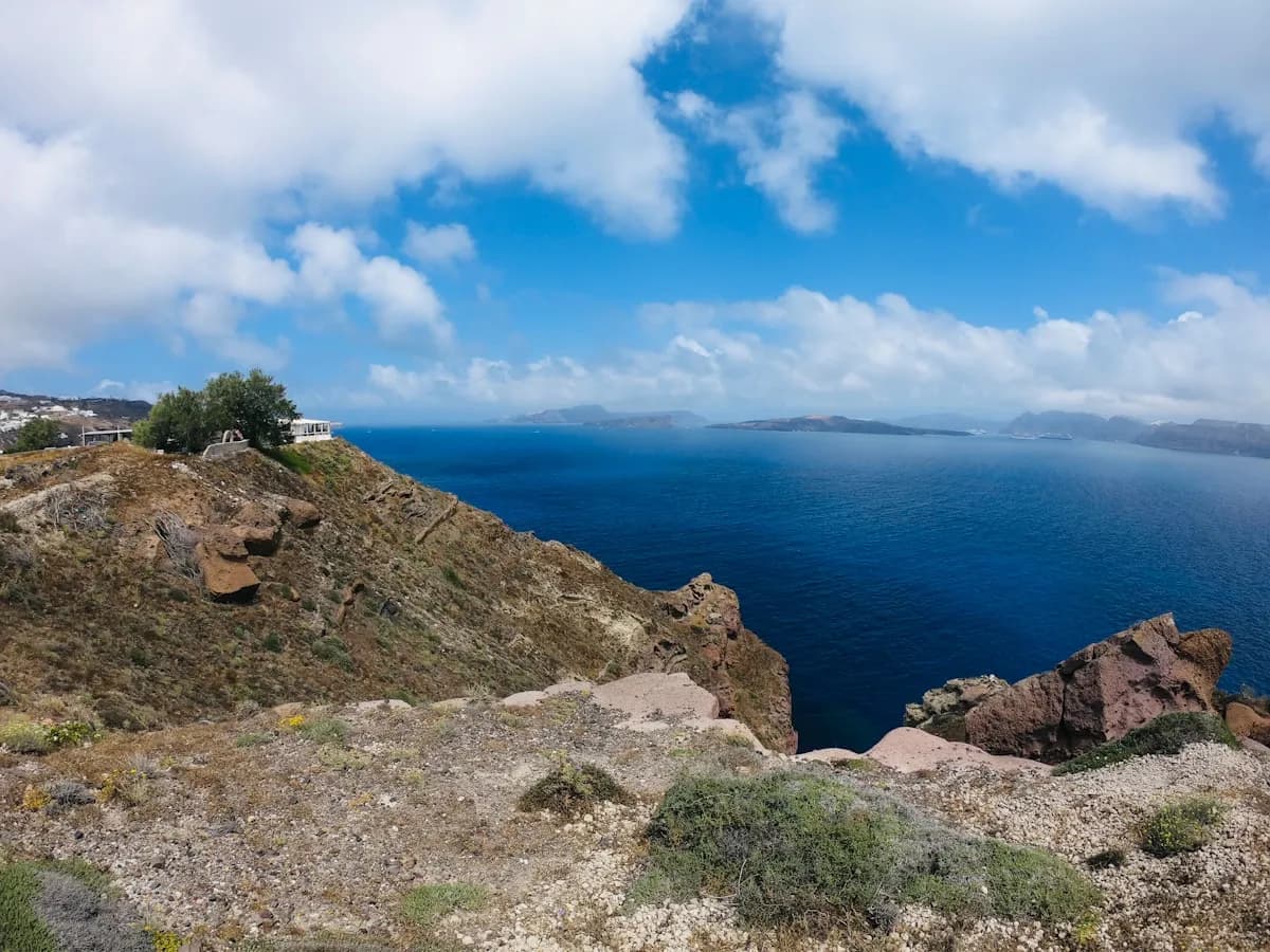 Rocky caldera cliffs of Santorini under dramatic clouds with the Aegean Sea below