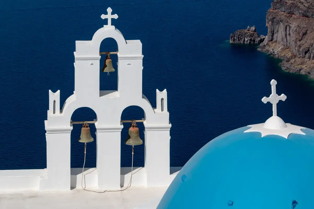 The Three Bells church in Firostefani: a white three-bell tower and a blue dome above the caldera