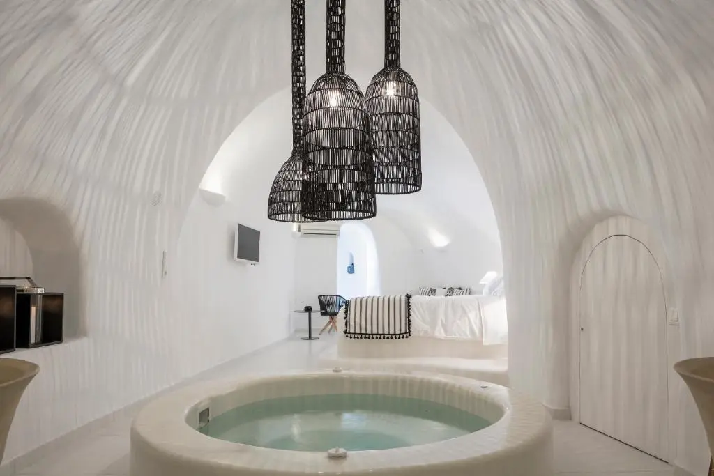 Vaulted cave-style suite interior with a round jacuzzi at Aroma Suites in Santorini