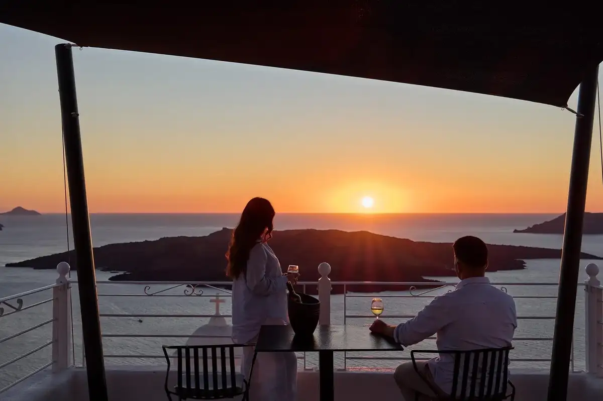 Couple watching sunset over the Santorini caldera from Aroma Suites terrace in Fira
