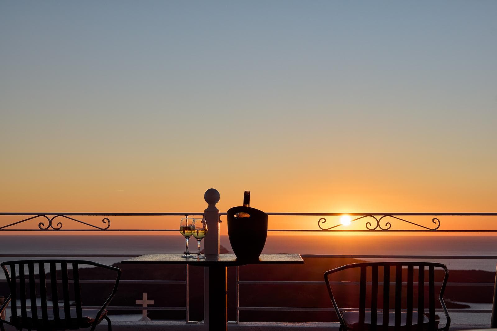 Church dome silhouette against golden Santorini sunset over the caldera