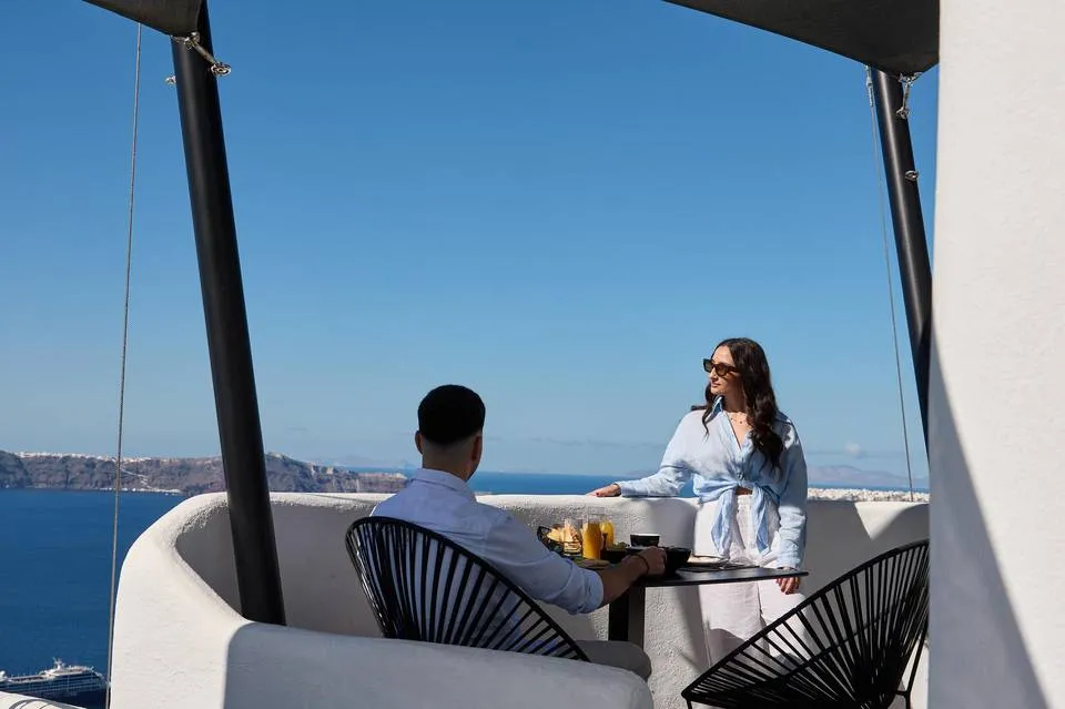 Couple relaxing on terrace with caldera view at Aroma Suites Santorini