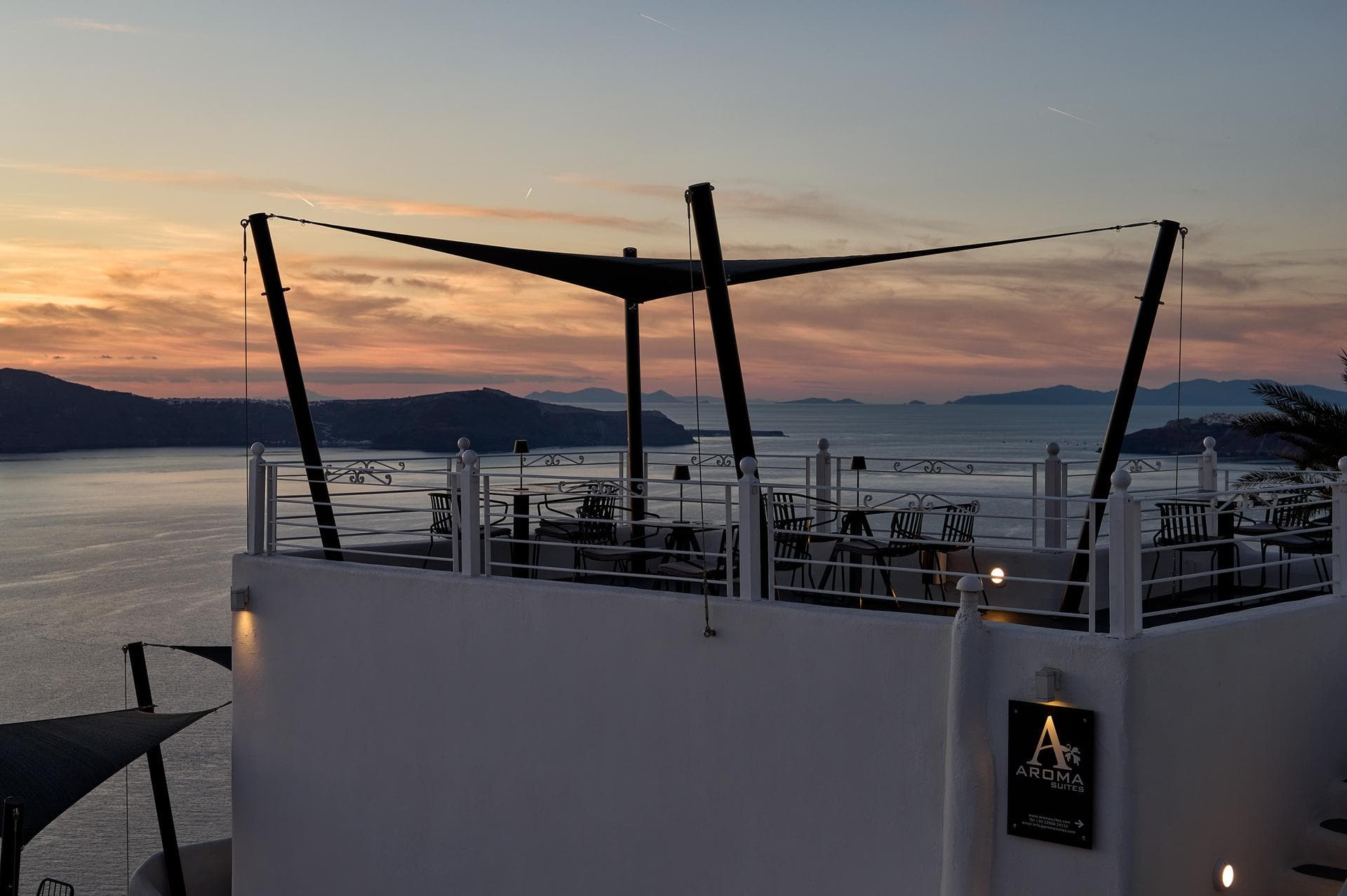 Rooftop terrace with sail shade at sunset at Aroma Suites Santorini