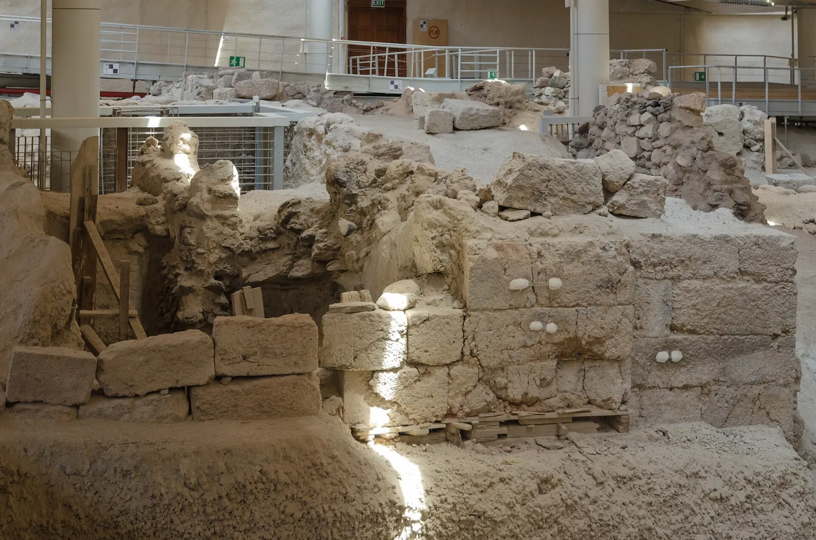 Excavated stone walls of a Bronze Age building at Akrotiri, under the site's roof