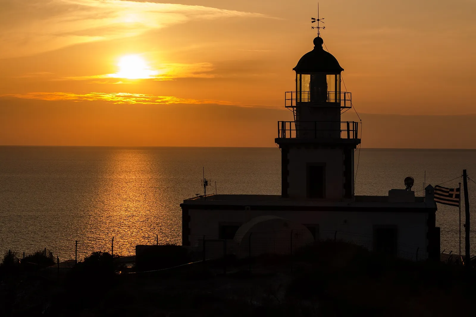Akrotiri lighthouse in silhouette as the sun sets over the sea