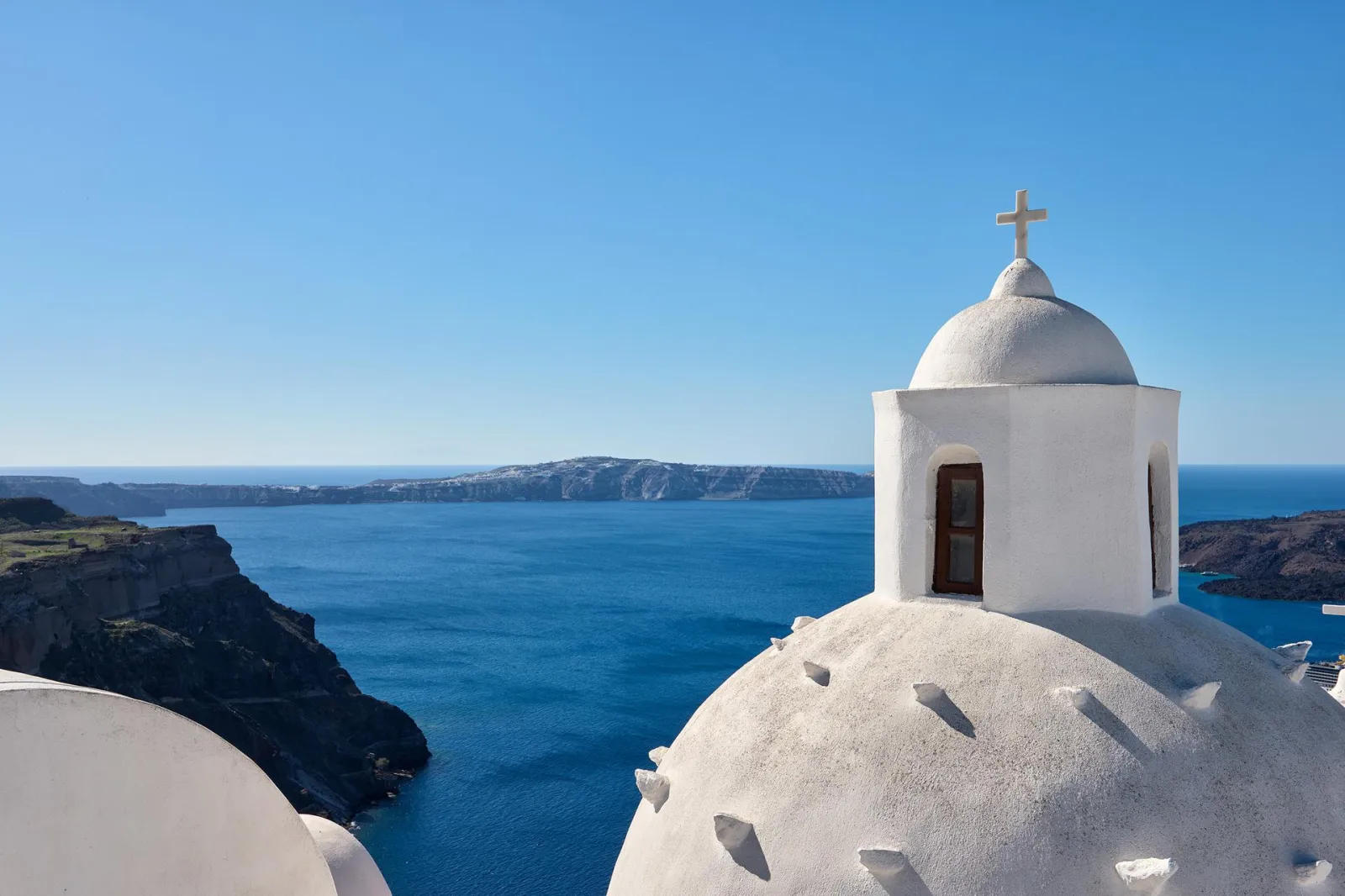 A white church dome and the blue caldera seen from a terrace at Aroma Suites in Fira