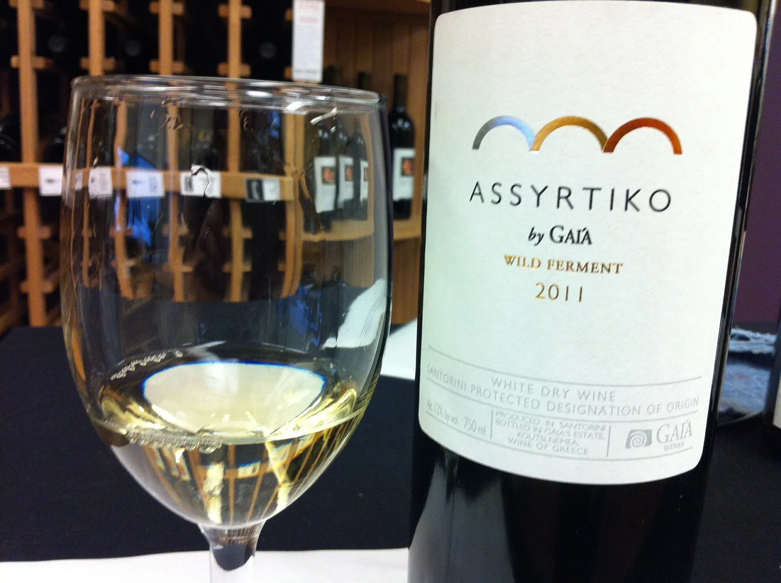 A glass of white wine beside a bottle of Gaia Wild Ferment Assyrtiko from Santorini