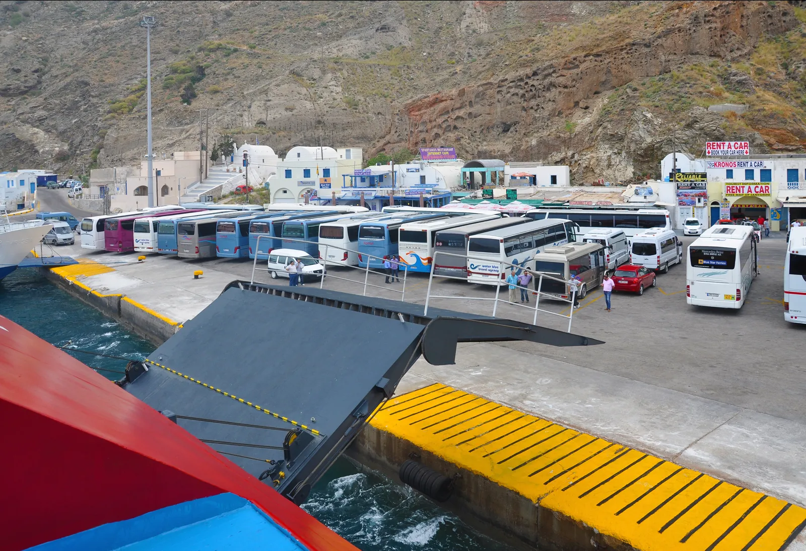 Ferry ramp lowered at Athinios port with buses waiting on the quay