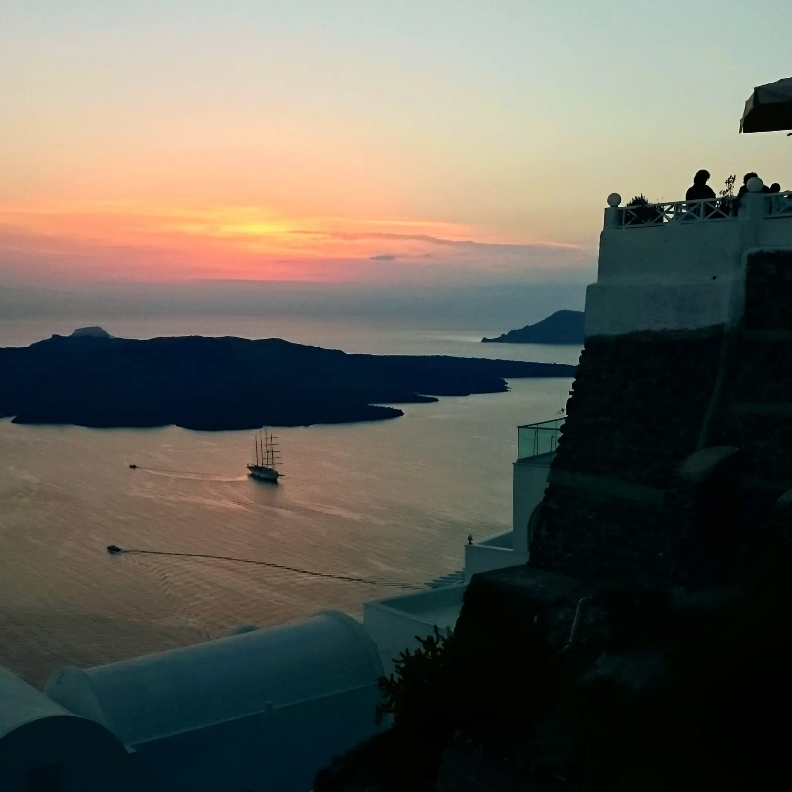 Sunset over the caldera from a terrace in Imerovigli, a sailing ship below
