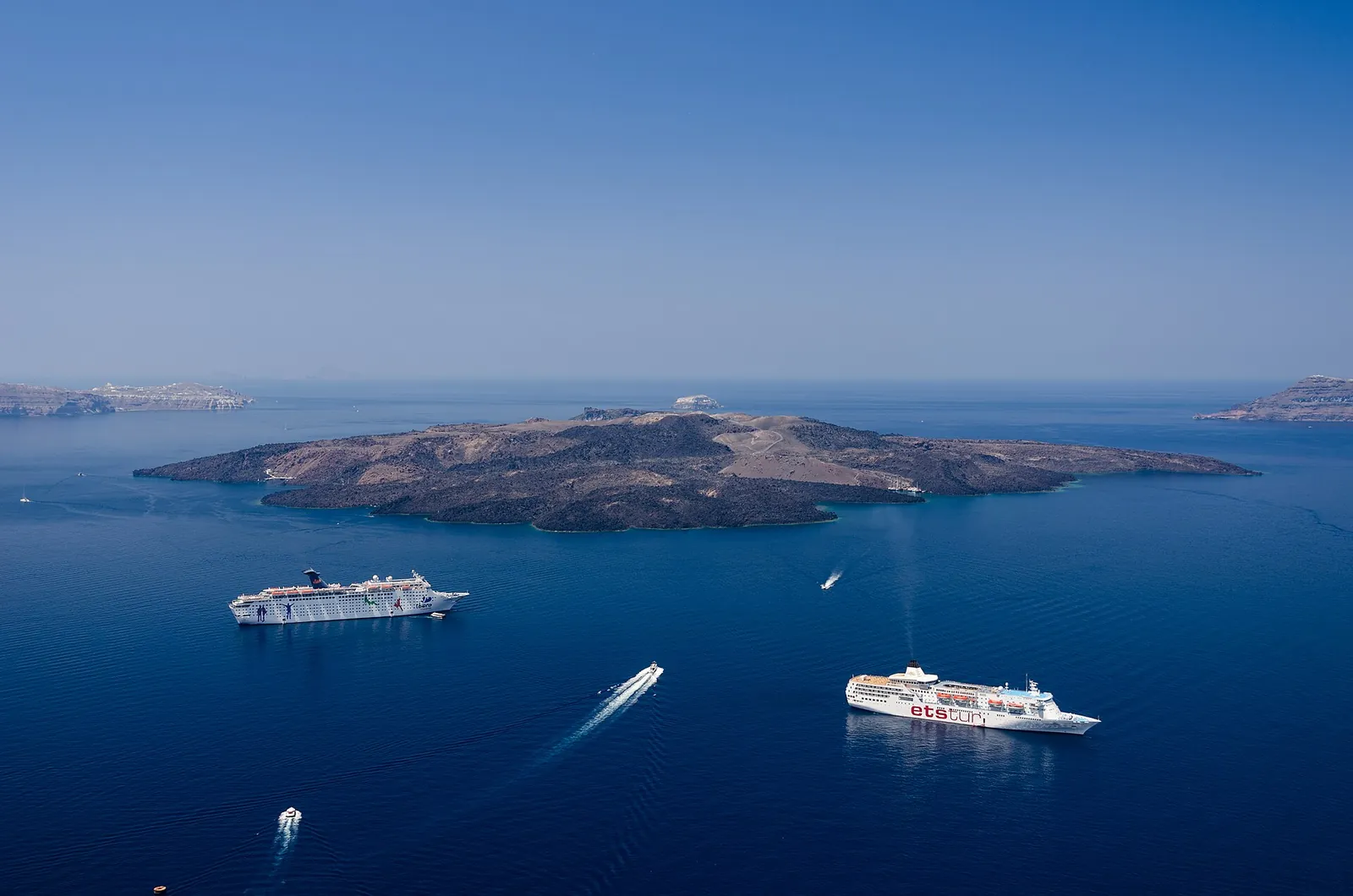 Two cruise ships anchored in the caldera off Nea Kameni, tender boats crossing