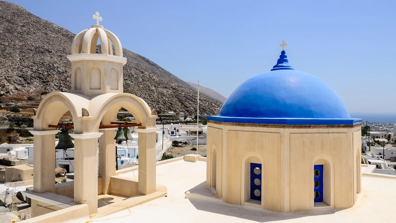 Blue church dome and a stone bell tower on the rooftops of Emporio
