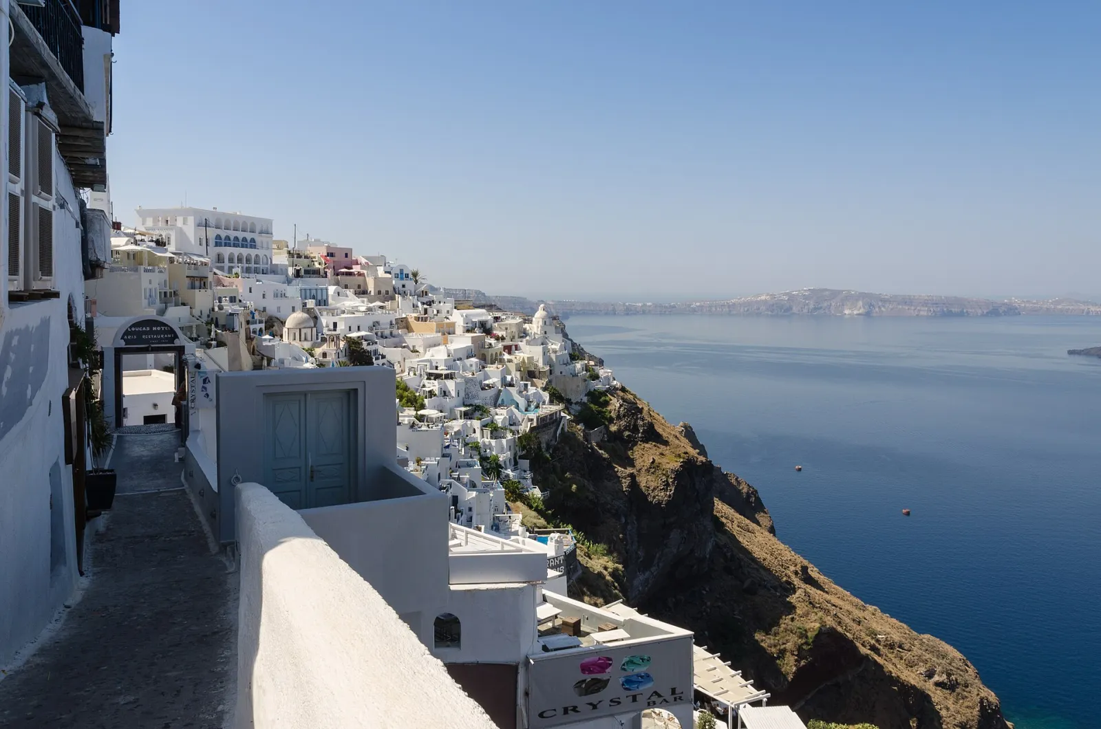 A lane along the caldera rim in Fira, whitewashed hotels stepping down the cliff