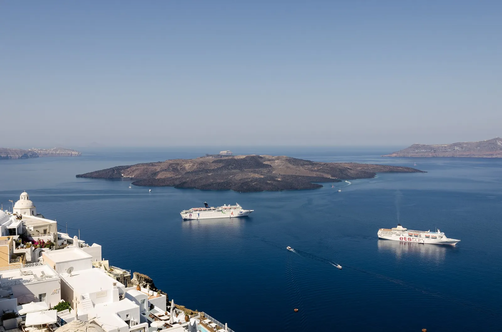 Fira's whitewashed houses on the caldera edge looking out over the volcanic island of Nea Kameni and two cruise ships