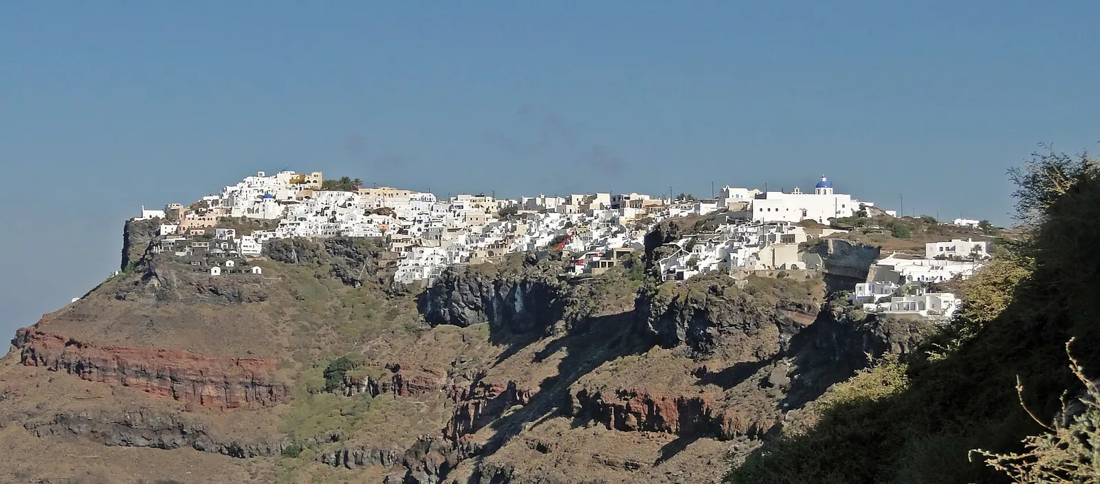 Imerovigli's white houses along the top of the caldera cliff, seen from Fira