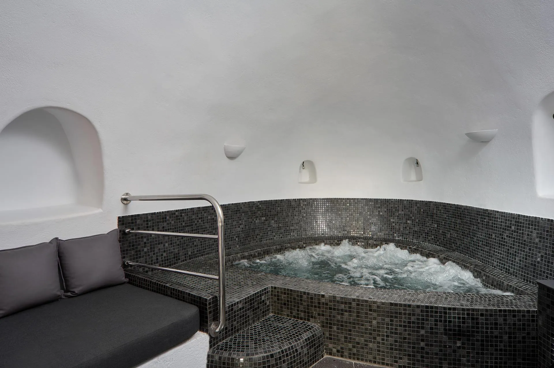 Indoor jacuzzi under a curved whitewashed cave ceiling at Aroma Suites in Fira