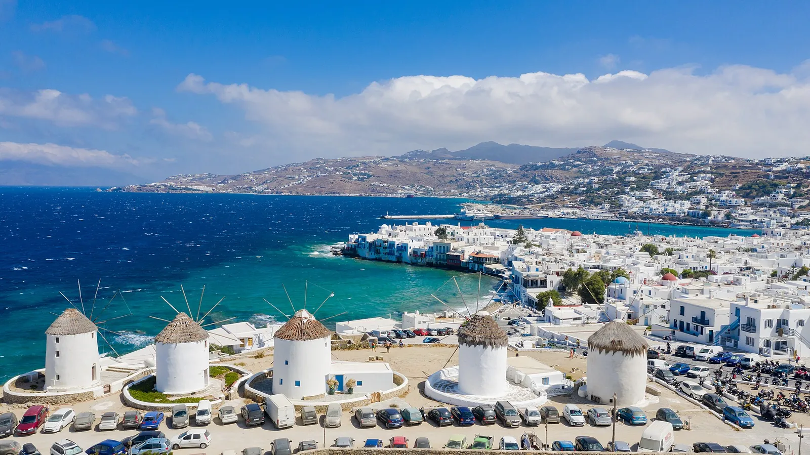 The row of white windmills above Mykonos town, with Little Venice and the harbour behind