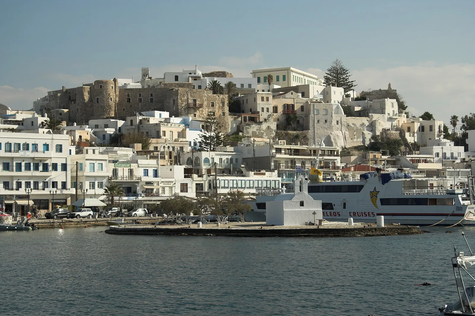 Chora of Naxos and its Venetian Kastro seen across the harbour from the main pier, with the small white chapel on its islet in front