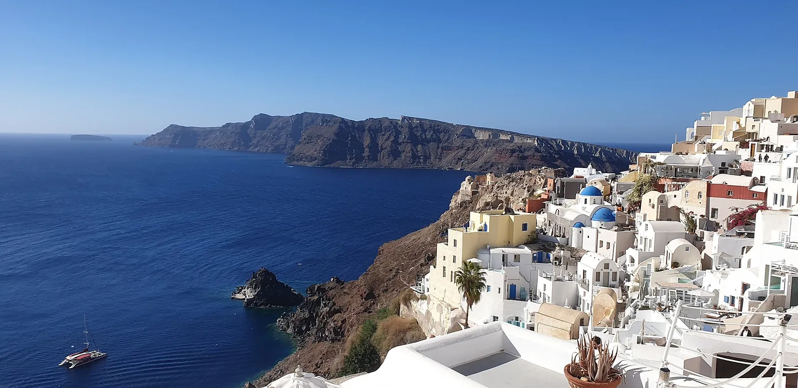 Oia's white houses and blue domes spilling down the caldera cliff above the sea