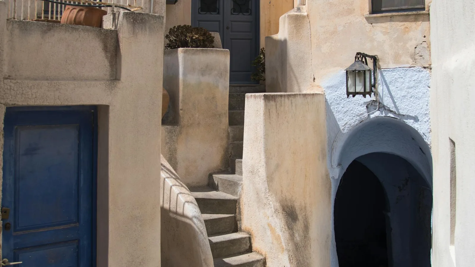 Cobblestone alley in Pyrgos medieval village with whitewashed walls, Santorini