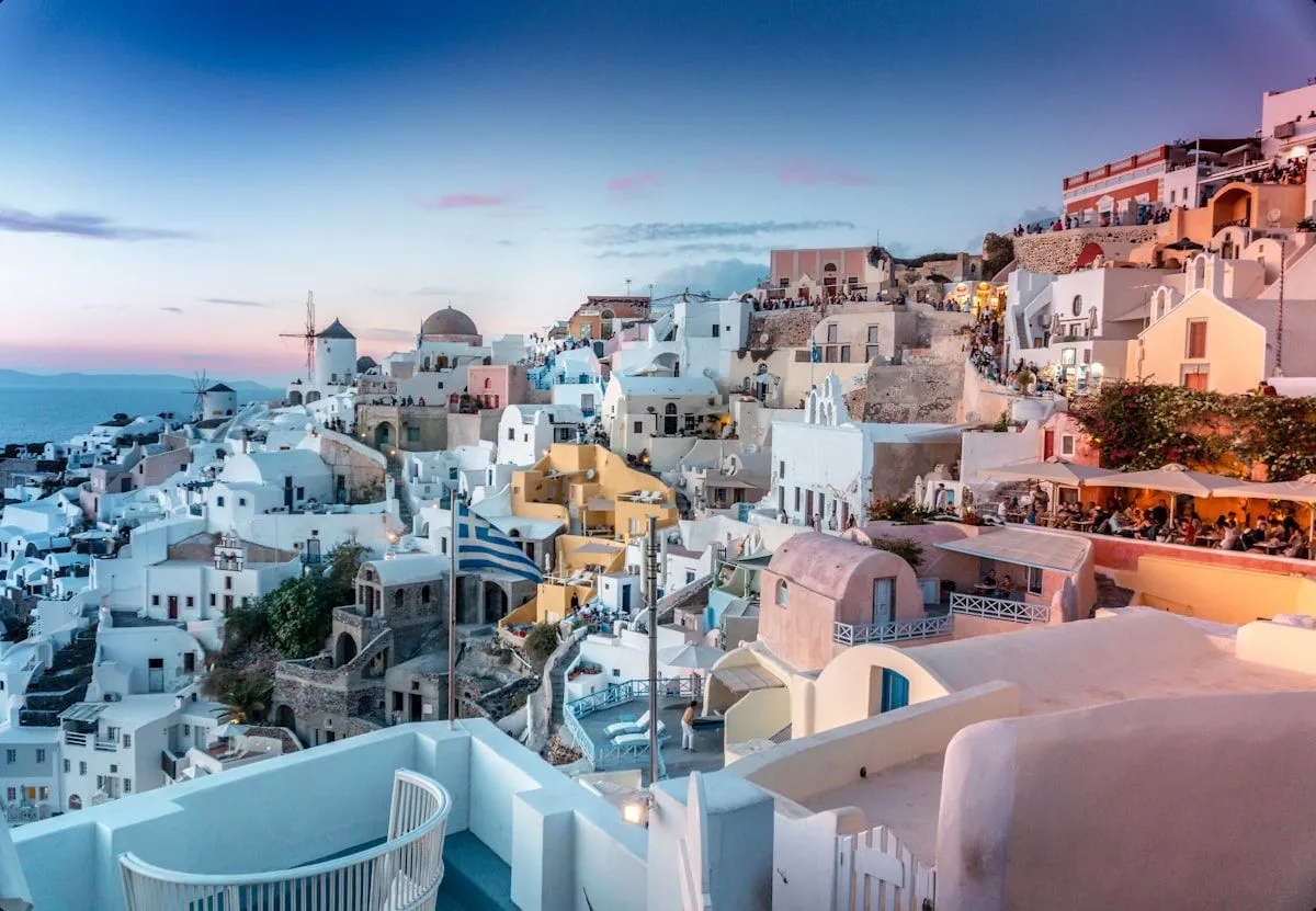 Oia's whitewashed houses and windmills stacked on the caldera cliff at dusk