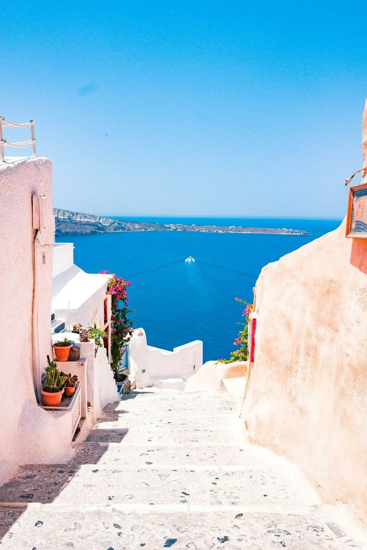 Narrow cobblestone street in Santorini lined with shops and bougainvillea