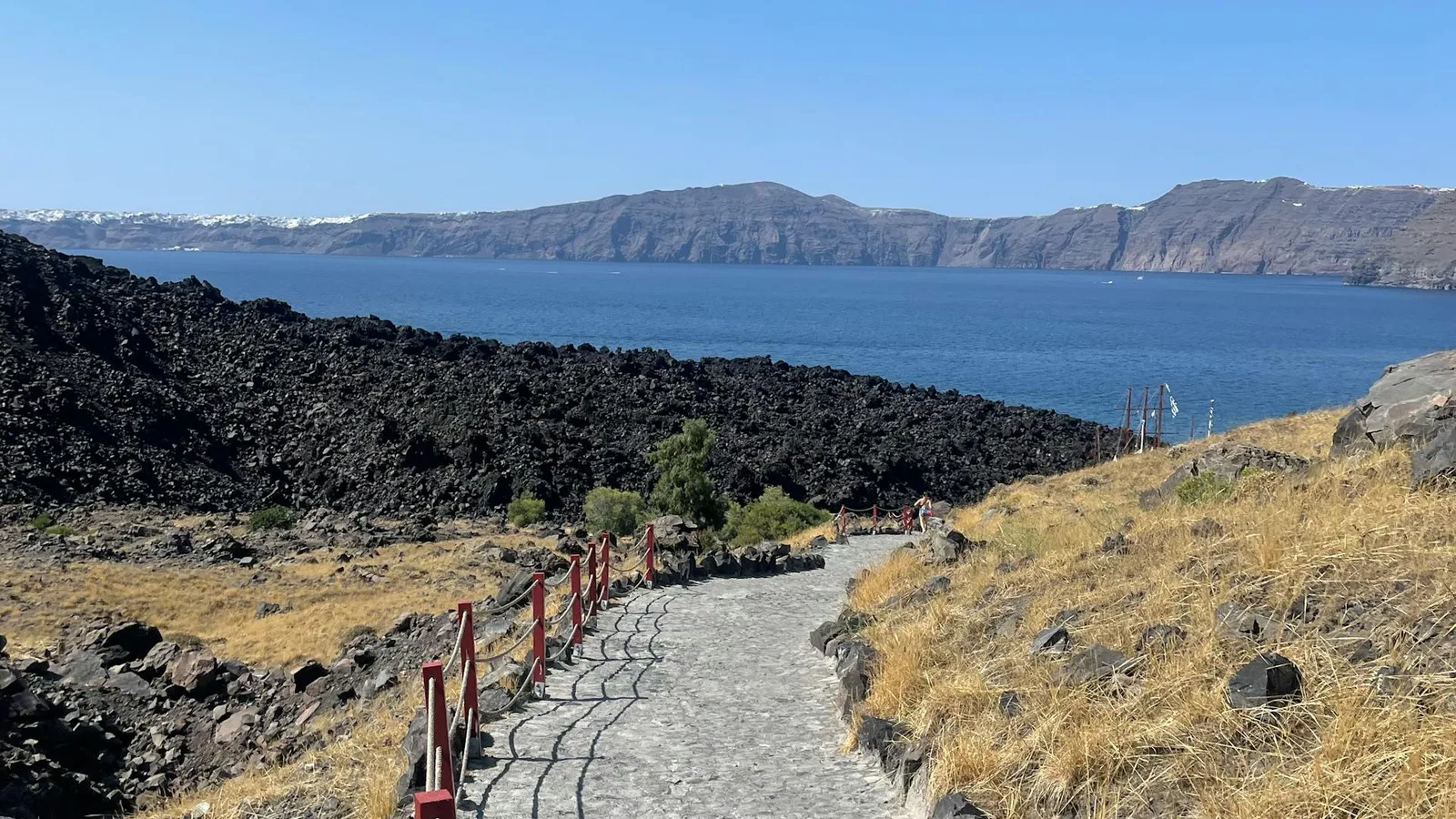 Volcanic trail on Nea Kameni island with Santorini caldera cliffs in the background
